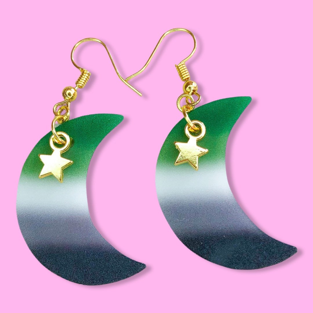 Shrinky dink moon earrings in the colours of the Aromantic pride flag with a gold star charm hanging at the top