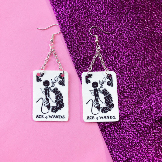 Black and white tarot card earrings. Original design based on Ace of Wands tarot card. A hand is coming out a cloud and holding a vibrator with the text ACE OF WANDS beneath