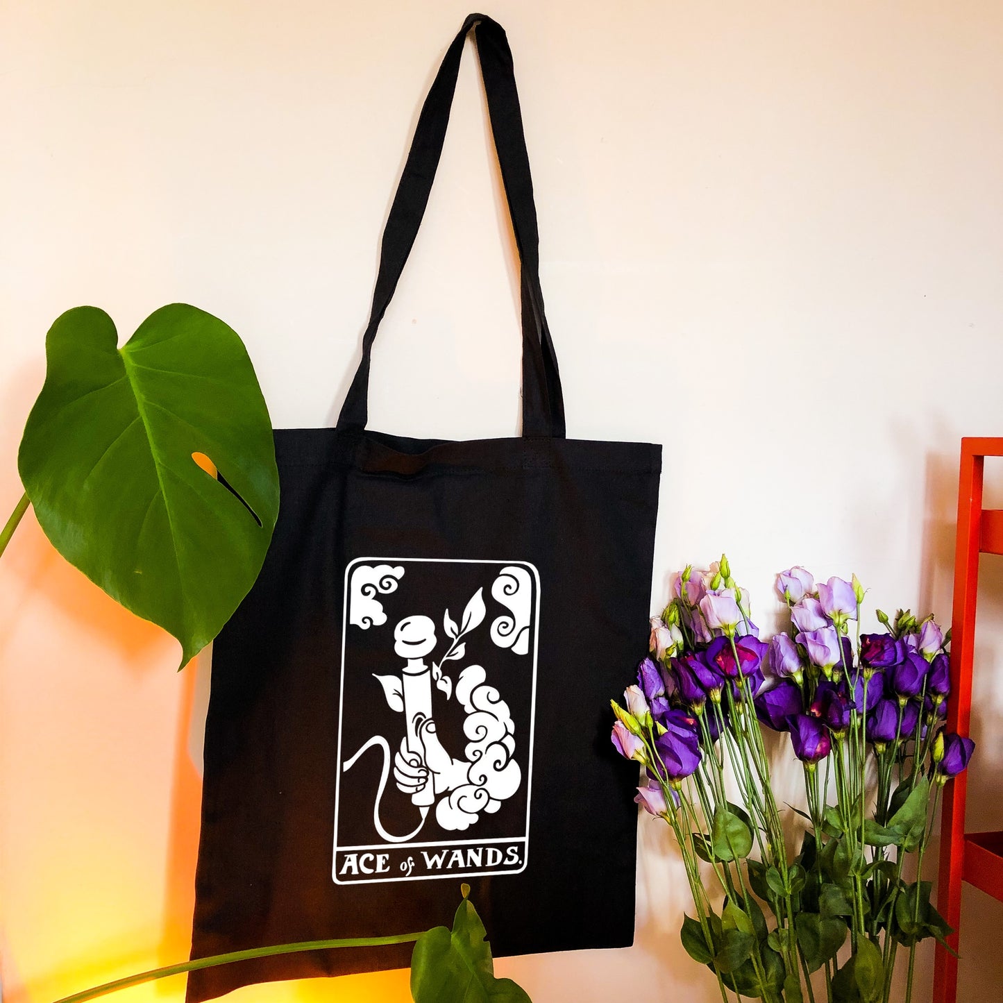 Black tote bag with white tarot card design. Original design based on Ace of Wands tarot card. A hand is coming out a cloud and holding a vibrator with the text ACE OF WANDS beneath