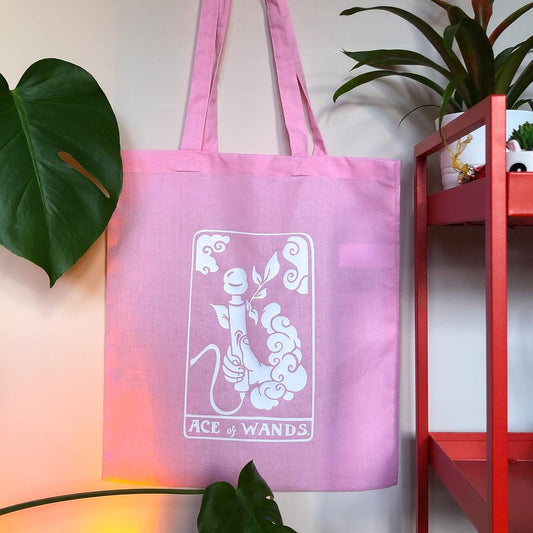 Pink tarot card tote bag with a white design. Original design based on Ace of Wands tarot card. A hand is coming out a cloud and holding a vibrator with the text ACE OF WANDS beneath